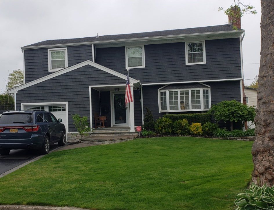 Navy colonial with white trim, an American flag and a cut lawn